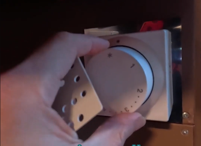 Mano che regola il termostato di un radiatore, impostando la temperatura su un livello intermedio.