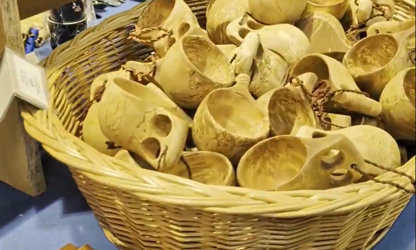 Cesto di vimini pieno di tradizionali kuksa con manici e fori per cordini.