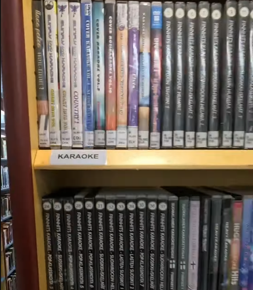 Scaffale pieno di DVD di karaoke, con titoli in finlandese come 'Finnhits Karaoke' e 'Suomirockin Helmät'.