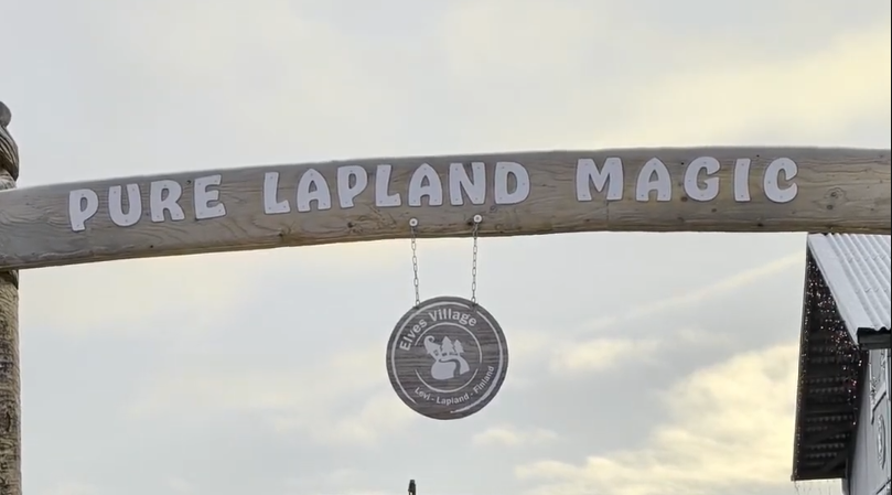 Arco in legno con la scritta "PURE LAPLAND MAGIC" e un cartello circolare "Elves Village Levi-Lapland-Finland".