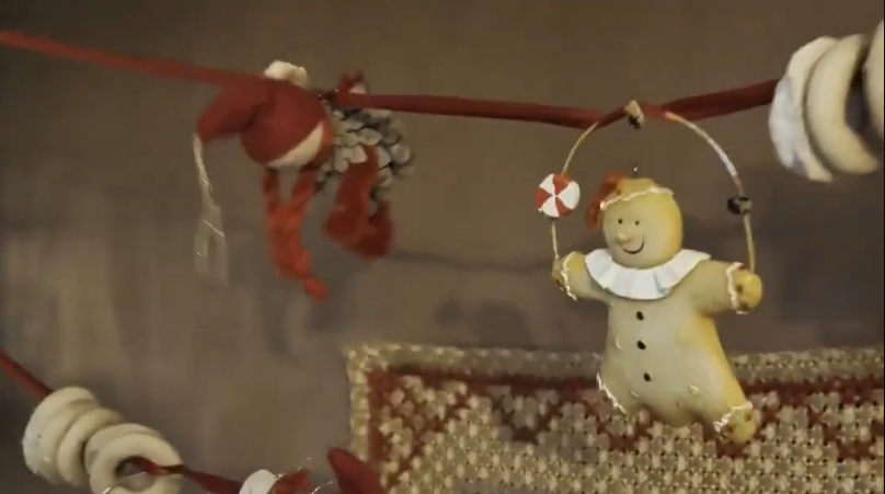 Decorazioni natalizie con un omino di pan di zenzero appeso e altri ornamenti rossi e bianchi.