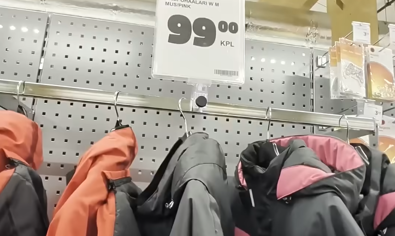 Giacche invernali appese su un espositore in un negozio, con un cartellino del prezzo di 99.00 KPL visibile.