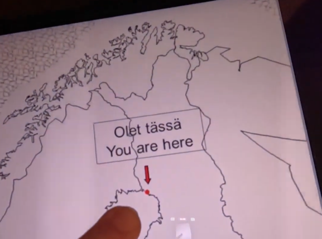 Dito che indica una posizione su una mappa con la scritta 'Olet tässä' e 'You are here'.