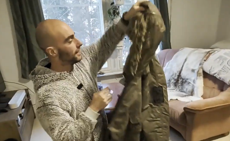 Stefano Mini tiene in mano un parka invernale verde.