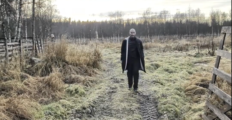 Stefano Mini cammina su un sentiero erboso e ghiacciato in un paesaggio rurale con alberi e una recinzione di legno.