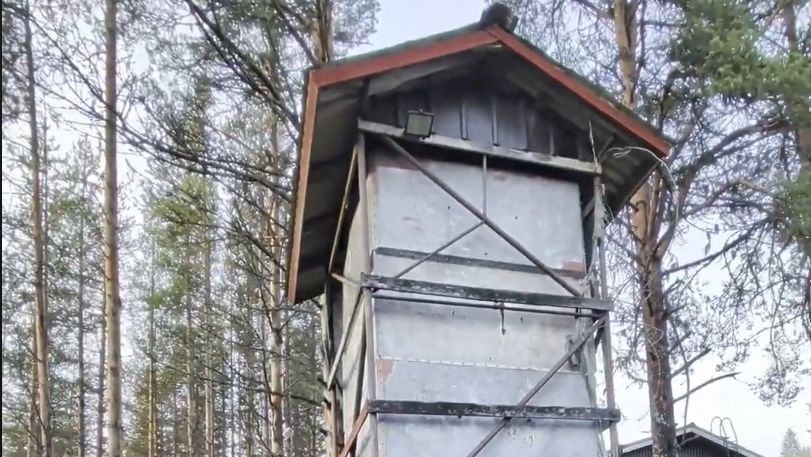 Silo per cibo delle renne alta e invecchiata con tetto rosso e pareti in lamiera.