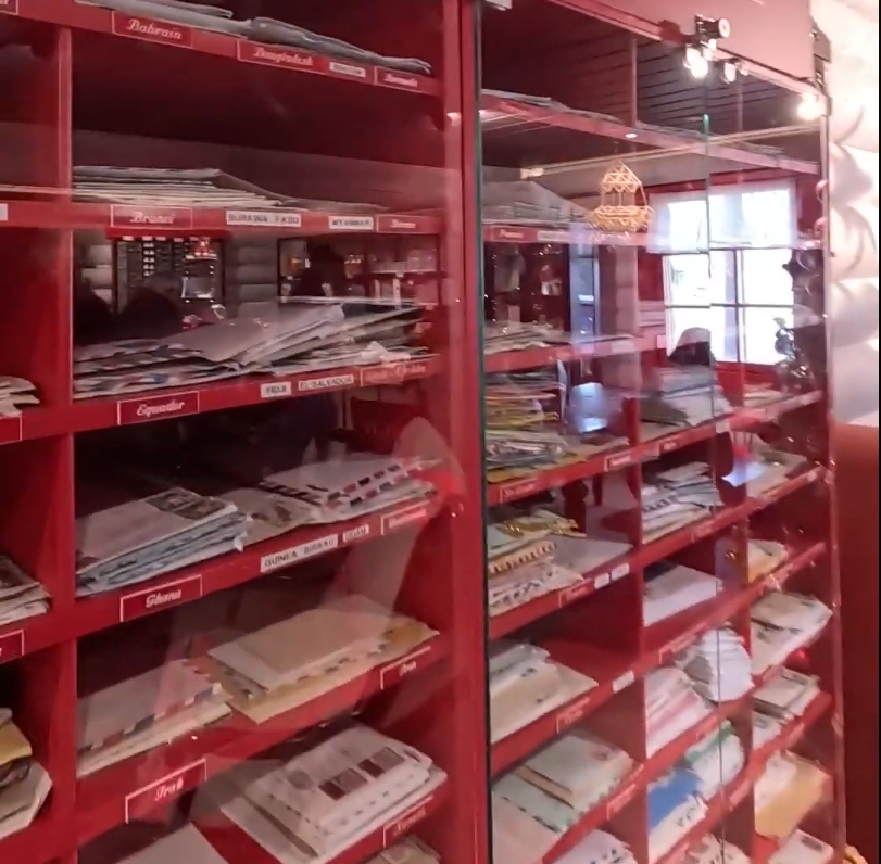 Due vetrine rosse piene di buste e francobolli da vari paesi come Bahrain, Ecuador e Ghana, esposti in una collezione filatel