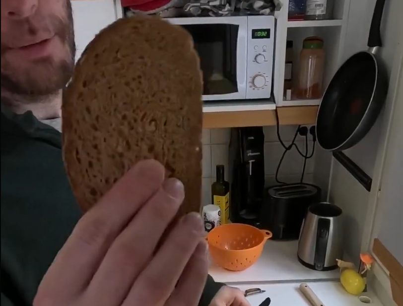 Stefano Mini tiene in mano una fetta di pane scuro in cucina.