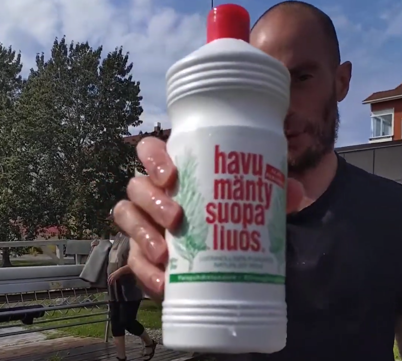 Stefano Mini tiene una bottiglia di sapone al pino finlandese "havu mänty suopa liuos" con la mano bagnata.