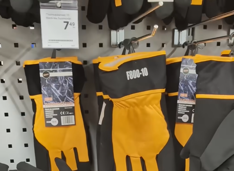 Guanti da lavoro neri e gialli appesi in un negozio, con un cartellino del prezzo di 7,49 euro e la scritta F800-10.
