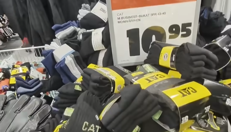 Display di calze nere a marchio CAT e calze colorate in un negozio, con un cartellino del prezzo di 10.95 euro visibile.