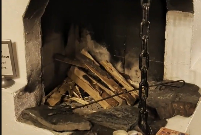 Camino in pietra con legna da ardere e attrezzi, pronto per accendere un fuoco accogliente.