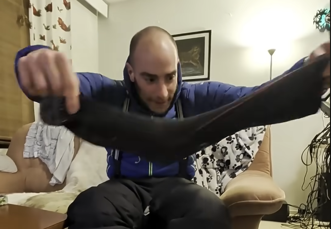 Stefano Mini seduto in casa che tiene in mano una calza invernale di lana.